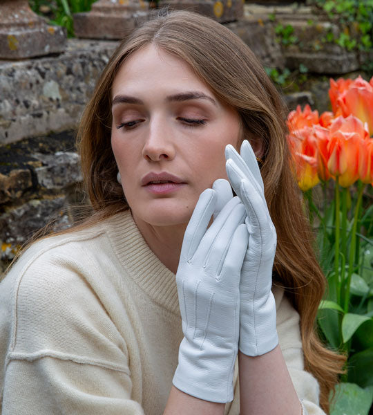 Woman wearing leather gloves in pearl sitting on a bench