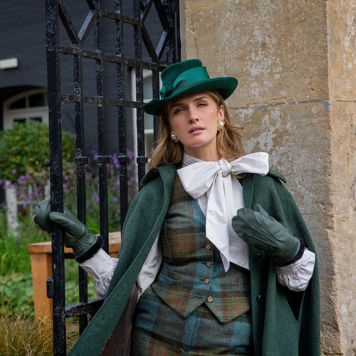 Woman wearing green leather mittens stood by an iron gate